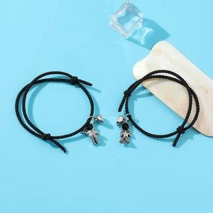 Detail of hand-woven astronaut couple bracelets with magnetic heart charm and silver pendants