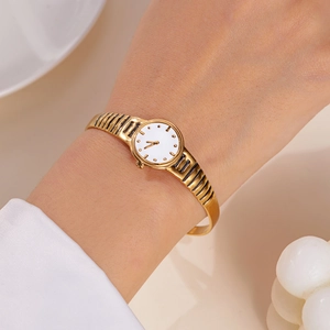 Close-up of vintage gold metal watch with hollow striped band on female wrist