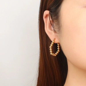 Polished gold-plated stainless steel hoop earrings on model with minimalist design