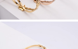 Detail of gold and rose gold titanium bracelets with butterfly charms and inset crystals