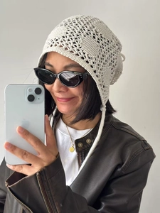 Détail d'un bonnet au crochet beige tricoté main avec motifs ajourés et lanières