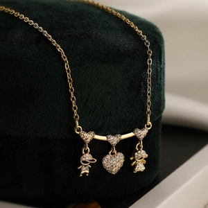 Gold plated necklace with heart pendant featuring zircon paved boy and girl figurines