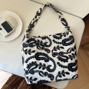 Detail of black paisley embroidery on white cotton linen shoulder bag with brand label