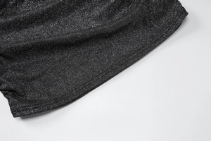 Détail du tissu noir à paillettes argentées et coutures soignées sur l'ourlet de robe
