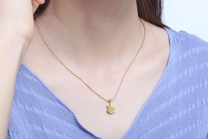 Close-up of a minimalist gold cat silhouette pendant necklace on a female model