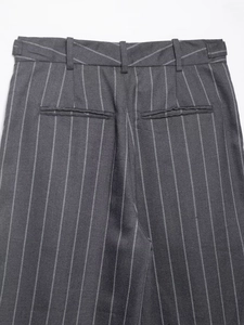 Detailed view of dark grey pinstriped trousers showing waist and rear welt pockets
