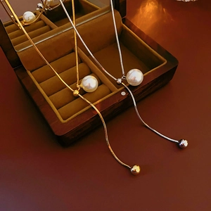 Detailed view of gold and silver snake chain necklaces with round pearls on a jewelry box