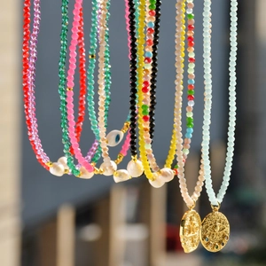 Detailed close-up of colorful crystal beaded necklaces with pearls and gold pendants