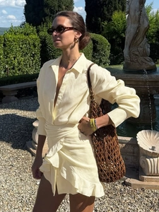 Pale yellow long sleeve shirt dress with wrap waist tie and ruffled hem for summer resort
