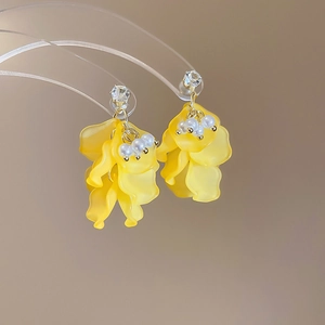 Dettaglio di orecchini a fiore con petali gialli satinati e perle bianche su metallo oro