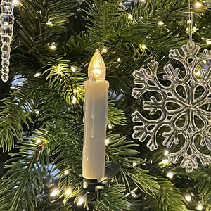 LED flicker candle with clip on Christmas tree branch featuring warm yellow light glow