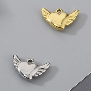 Detailed view of heart-shaped angel wing pendants in polished gold and silver finishes