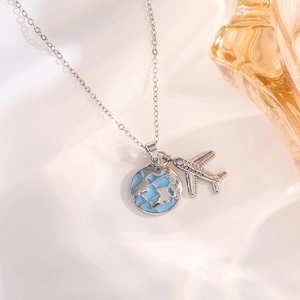 Macro shot of silver airplane and light blue globe pendants on a stylish chain