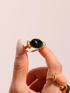 Close-up of a gold-plated adjustable ring with a large oval black resin gemstone