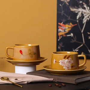 Detail of yellow ceramic floral coffee cup set with cherry blossom and leaf patterns