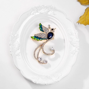 Detailed shot of gold phoenix brooch with blue teardrop gemstone and enamel tail