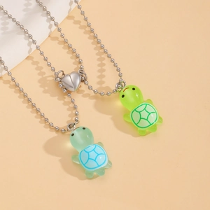 Close-up of heart magnetic clasp connecting two luminous turtle pendant necklaces