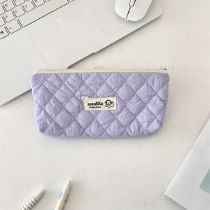 Top view of a lavender quilted pencil case on a desk with laptop and office accessories