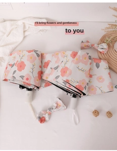 Detail of pink floral folding umbrella with decorative bow and white minimalist handle