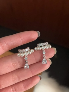 Detailed shot of teardrop zircon and pearl drop earrings with elegant silver metal base