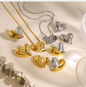 Macro detail of gold and silver heart-shaped necklaces and earrings set on beige fabric