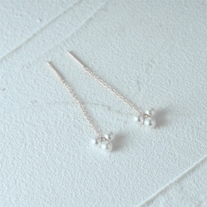 Macro detail of S925 silver long tassel earrings featuring a white triple pearl cluster