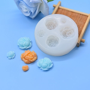 Detail of round silicone mold with four rose shapes and finished resin flower models