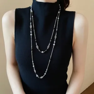Multi-layer silver pearl necklace featuring hollow flower accents on black knitwear