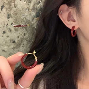 Macro shot of minimalist red enamel C-shape hoop earrings worn by a model in detail