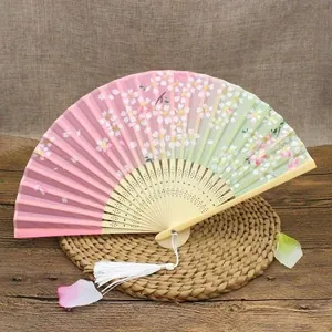 Detail of a cherry blossom folding fan with pink gradient and long white silk tassel
