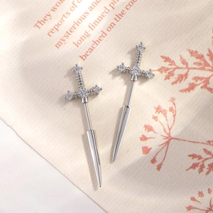 Silberne Schwert-Ohrstecker mit Zirkon-Besatz auf strukturiertem Hintergrundpapier
