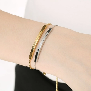 Detailed view of adjustable metal bracelet with engraved LOVER DREAM text on gold and silver bands