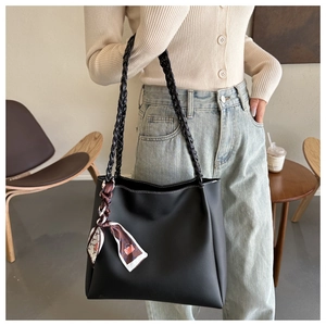 Detail of black tote bag with woven straps, contrast stitching, and vintage silk scarf