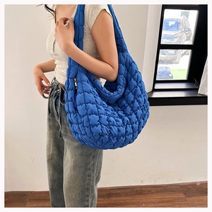 Detail of a bright blue quilted cloud hobo bag showing its puffy nylon texture and strap