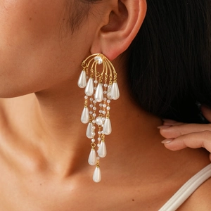 Close-up of elegant gold tassel earrings with teardrop pearls and zircon crystals