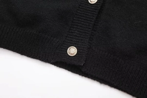 Detailansicht goldener Löwenknöpfe auf schwarzen gerippten Strickjackenbündchen