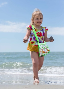 Close-up of a child wearing a green mesh beach bag with colorful dinosaur and sea animal prints