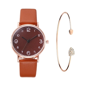 Close-up of rose gold watch with brown leather strap and heart-shaped rhinestone bracelet