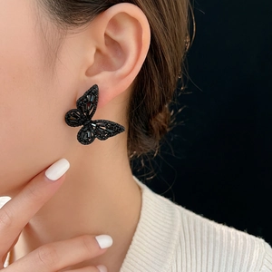 Elegant black butterfly stud earrings featuring micro-set crystals on model ear