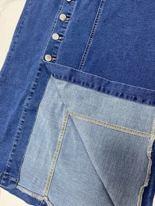 Détails de la jupe en jean bleu foncé avec boutons métalliques argentés et ourlet fendu