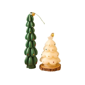 Miniature green and white Christmas tree candles with colorful dots on a wooden base