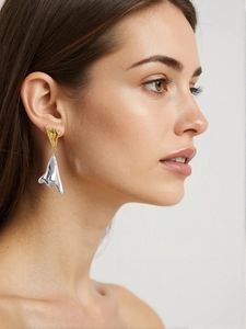 Gros plan de boucles d'oreilles bicolores or et argent au design métal liquide