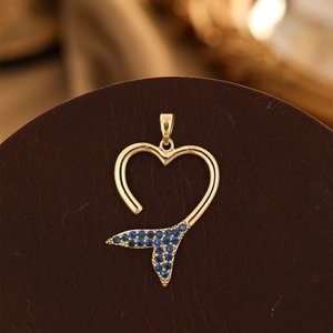 Détail du pendentif en forme de cœur doré avec cristaux bleus en motif queue de sirène