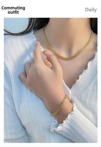 Detail shot of a gold wheat-pattern chain necklace and bracelet set on a model
