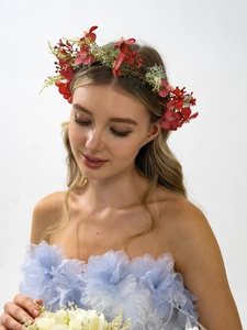 Floral headband crown with red and green artificial flowers worn by a model in a light blue dress