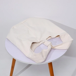 Close-up of thick beige canvas shoulder bag featuring a unique knotted strap design