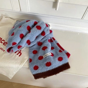 Close-up of soft blue faux mink scarf featuring large red polka dots and a brand label