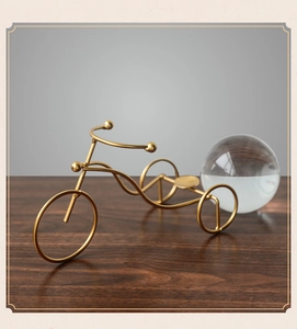 Detailed view of modern gold metal tricycle sculpture with polished finish for home decor
