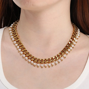 Close-up of gold Cuban link necklace with dangling white pearls worn by a model