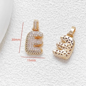 Macro view of gold letter E pendant with cubic zirconia and dimensions 30mm by 15mm
